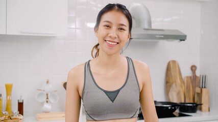 Portrait of young Asian blogger lady exercise and looking to camera in kitchen, Attractive beautiful indian female working out for healthy at home. Woman exercise at home concept.