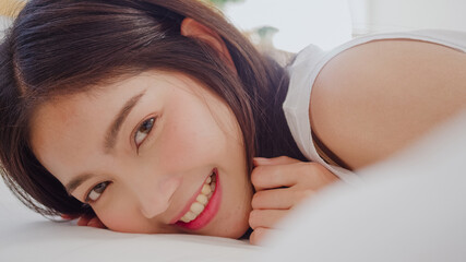 Asian woman smiling lying on bed in bedroom, Beautiful japanese female using relax time after wake...