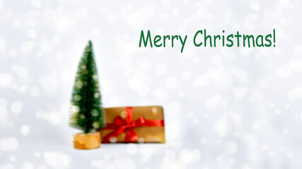 defocused lights and Christmas tree and defocused gift. Blurred completely. Copy space. blurred background on the theme of christmas and new year. Christmas card. green lettering Merry Christmas.
