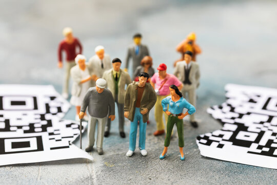 Toy men made of plastic and a sheet torn in half with a barcode, the concept of people against the introduction of the system of QR codes