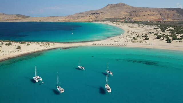 Aerial drone top down video of organised with sun beds and umbrellas paradise sandy beach of Simos with crystal clear turquoise sea, island of Elafonisos, Lakonia, Peloponnese, Greece