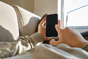 A man holds a smartphone in his hands in bed and checks a social network account before going to bed or after waking up. Gadget addiction. Man sending a text message on a mobile phone