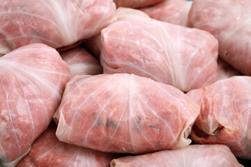 Uncooked stuffed cabbage rolls as background, closeup view