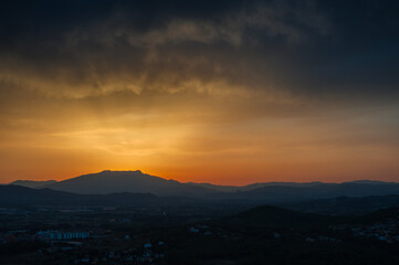 A silhouette of a mountain against a sunset sky