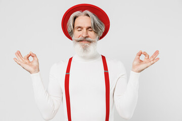 Elderly gray-haired mustache bearded man 50s in turtleneck red hat suspenders hold spread hand yoga...