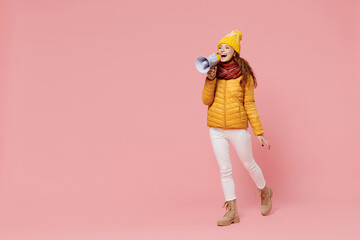 Full size body length promoter young woman 20s wear yellow jacket hat mittens hold scream in megaphone announces discounts sale Hurry up isolated on plain pastel light pink background studio portrait