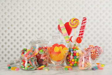 Jars with different delicious candies on white marble table