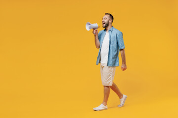 Full body young caucasian man 20s in blue shirt white t-shirt hold scream in megaphone announces discounts sale Hurry up isolated on plain yellow background studio portrait. People lifestyle concept.