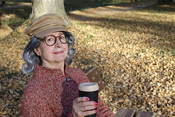 Senior lady holding coffee to go in autumn