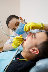 The dentist in the office treats the teeth of the patient who is in the dental chair. dentistry. The dentist puts a dental filling on his patient. Oral care