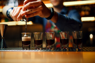 Barman makes cocktail shots b-52