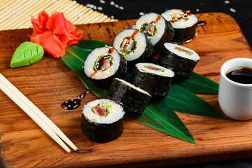 Sushi rolls with tuna and salmon on wooden board on a dark background