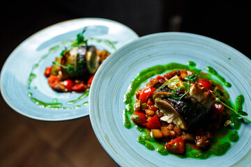 Fish dish - roasted fish and vegetables on a blue plate on a dark background
