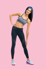 Fototapeta na wymiar Full body portrait image of young happy smiling bright vivid blue haired slim woman doing fitness stretching exercise, isolated over rose pink color background.
