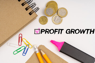 On a white background notepads, paper clips, coins, pencils and the inscription - PROFIT GROWTH