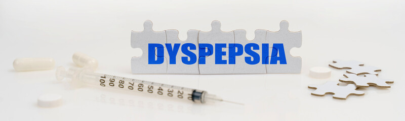 On a white background lie a syringe, pills and puzzles with the inscription - DYSPEPSIA