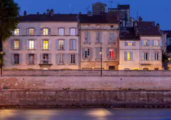 Arles. City embankment and facades of old houses at sunset.