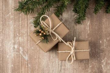 detail of gift boxes wrapped in paper with a cord bow and a small ornament, background with wood texture and tree branch, detail of the texture in studio, celebration wallpaper