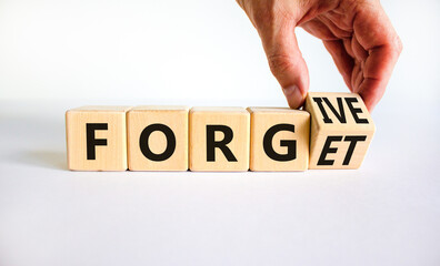 Forgive and forget symbol. Businessman turns a wooden cube and changes the word forgive to forget....