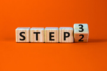 Step 2 or 3 symbol. Turned a wooden cube and changed words Step 2 to Step 3. Beautiful orange table, orange background, copy space. Business and Step 2 or 3 planning concept.