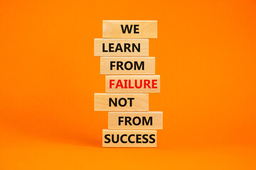 Failure or success symbol. Wooden blocks with words We learn from failure not from success. Beautiful orange background, copy space. Business, learn from failure or success concept.