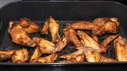 Finished chicken wings in the bowl of an air fryer. New technologies for healthy home nutrition