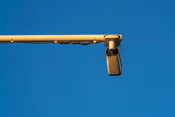 Outdoor video surveillance camera for traffic on the highway in the evening sun against the backdrop of a clear blue sky
