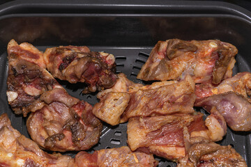 In the bowl of the air fryer, raw pork ribs for instant cooking