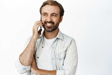 Portrait of young bearded man talking on mobile phone, making telephone call, standing over white background. Cellular technology concept