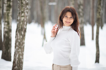 Portrait of a beautiful European woman in a winter forest, the woman has long hair, celebrating Christmas and New Year.
