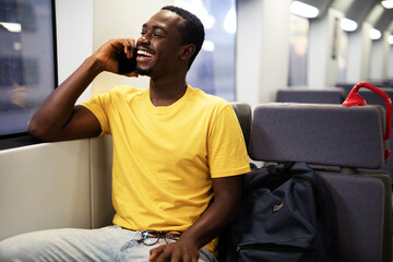 Young man travel by train. Handsome african man talking to the phone