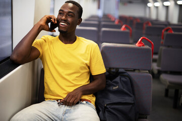 Young man travel by train. Handsome african man talking to the phone