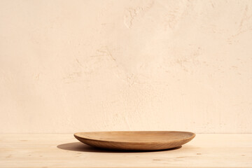 Round wooden bowl or podium for food, products or cosmetics against bright brown background.