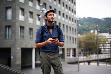Young stylish man using the phone outdoors. Fashion happy guy enjoy outdoors.