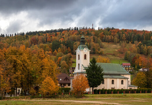 The church in Brenna under a threatening autumn sky among plants with autumn leaves
