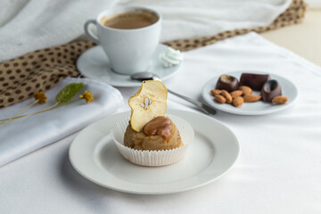 Apple cake with caramel sauce topping served on plate with cup of coffee on the table