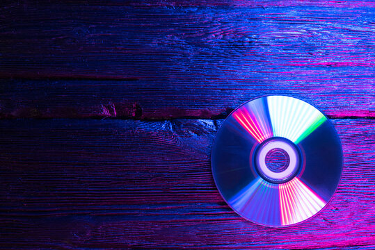 CD disk in the neon lights on the table background with copy space.