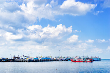 Ferry landing pier with fishing ship. Landscape with blue sea and sky.