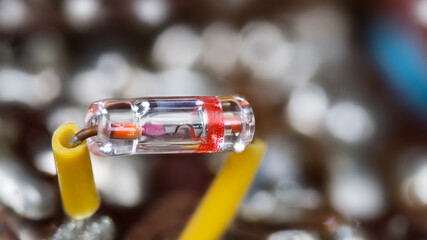 Closeup of old germanium point-contact diode in sealed glass tube. Retro electrical component in...