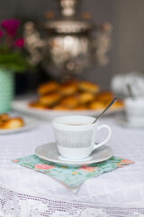 Russian traditional teaparty with samovar and pies or pirozhki with apple jam on white platter on white tablecloth 
