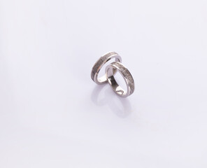 White gold rings with a meteorite insert on a white background © Elena