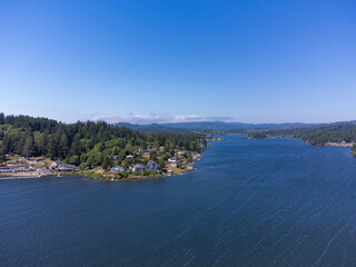 Fototapeta premium Aerial view. Picturesque landscape. Small town, a lot of greenery on the banks of a large river. Small houses, mountains can be seen in the distance. Housing issue, ecology.