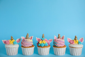 Many cute sweet unicorn cupcakes on light blue background