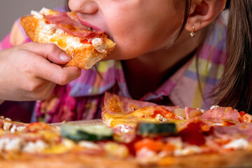 Young beautiful attractive girl enjoys delicious slice of  pepperoni pizza. Horizontal image.