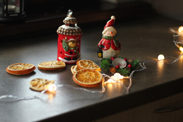 Christmas decor on the table. Flashlight, garland, dried orange, snowman