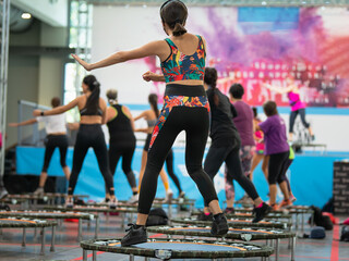 Mini Rebounder Workout: Girls doing Fitness Exercise in Class at Gym with Music and Teacher on Stage
