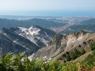 View of the marble Quarries of Carrara, the paths carved into the side of the mountain and the town of Carrara and the Coast in front of it