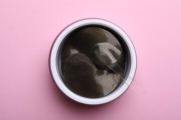 Package of under eye patches on pink background, top view. Cosmetic product