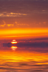 Bloody sunrise in the sky and dramatic clouds with the sun rising over the sea.