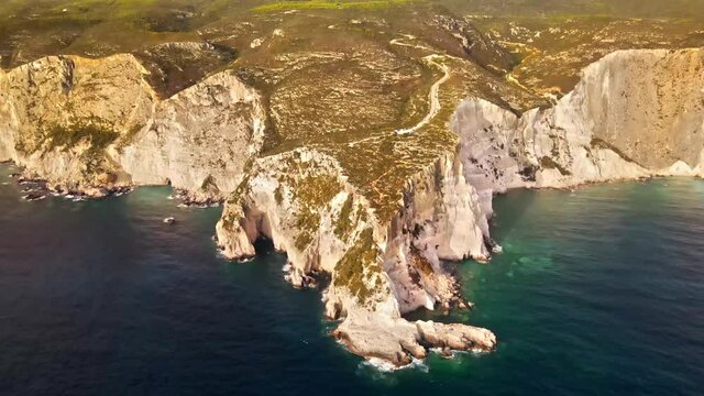 Aerial drone view of the Ionian Sea coast of Zakynthos, Greece. Rocky ridge, sparce vegetation, blue water. Sunset